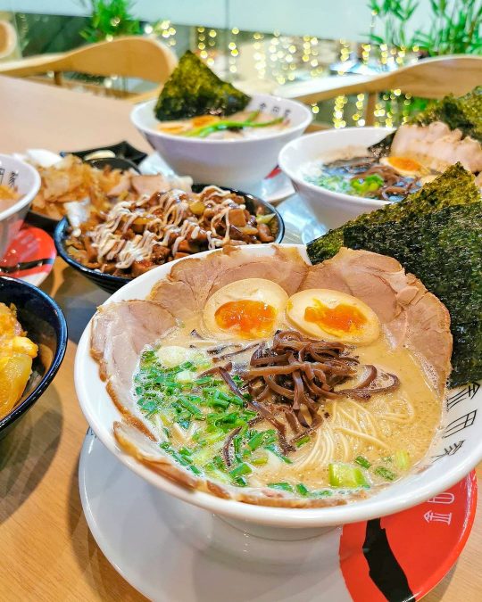 a table filled with bowls of award-winning Tonkotsu Ramen and sides