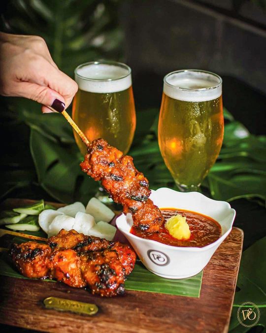 a plate of juicy, meaty satay with peanut sauce on the side and two beers
