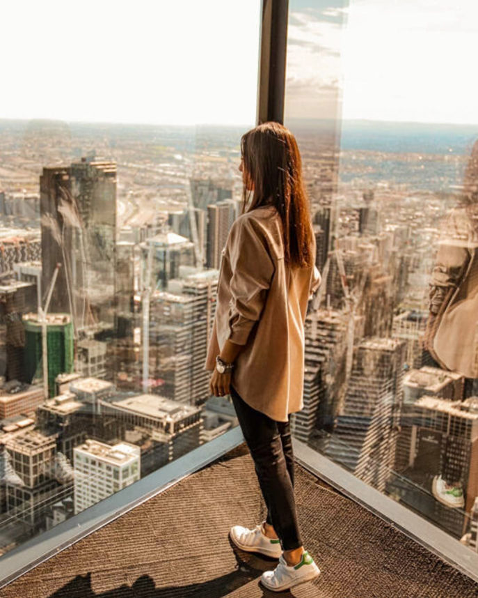 a woman stands on an observation deck of Melbourne Skydeck overlooking the city of Melbourne, Australia