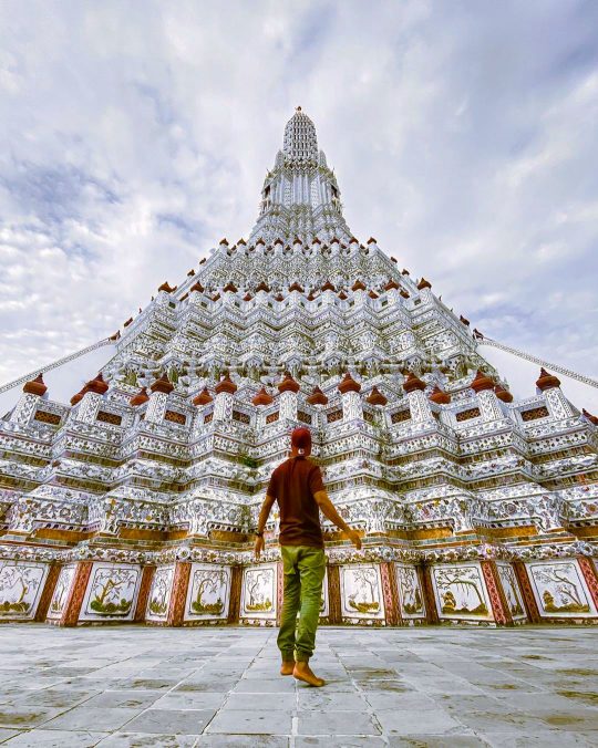 a person admiring the stunning architecture of Wat Arun Buddhist Temple in Bangkok