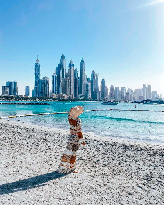 a person enjoying the view of Dubai city skyline from Palm West Beach