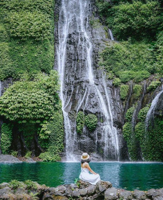 a woman appreciating the beautiful cascading waterfall in Munduk