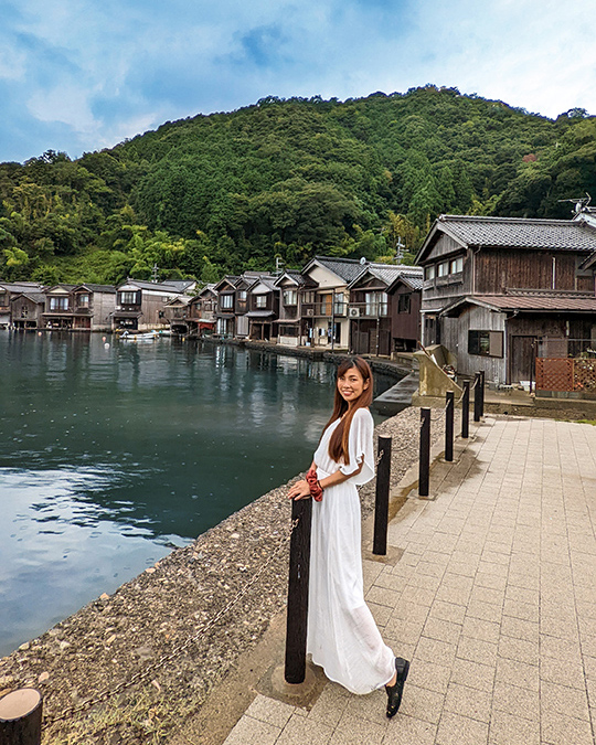 a woman in a white dress on a wooden walkway in the traditional fishing village Ine