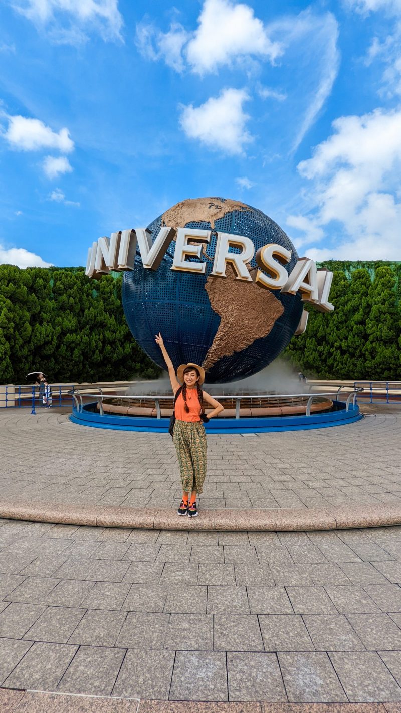 a woman standing in front of the universal studios osaka sign