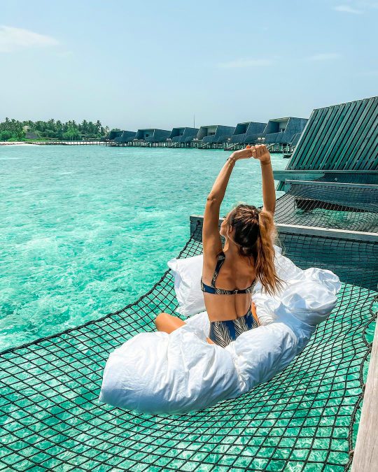a woman relaxing in a hammock at The St. Regis Maldives Vommuli Resort