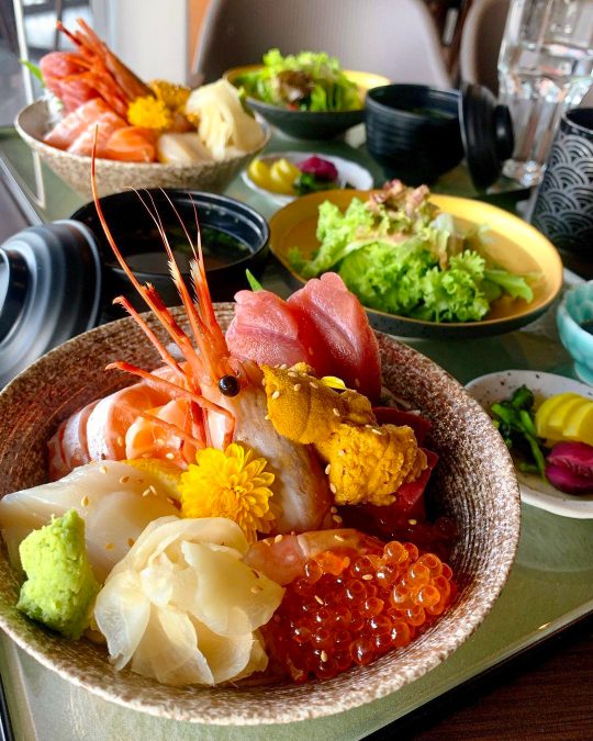a bowl of rice filled with a variety of exquisite fresh sashimi