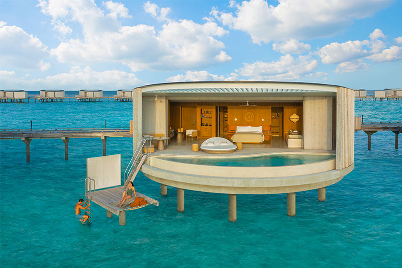 A man and woman relaxing outside of the hotel room that is build over the waters