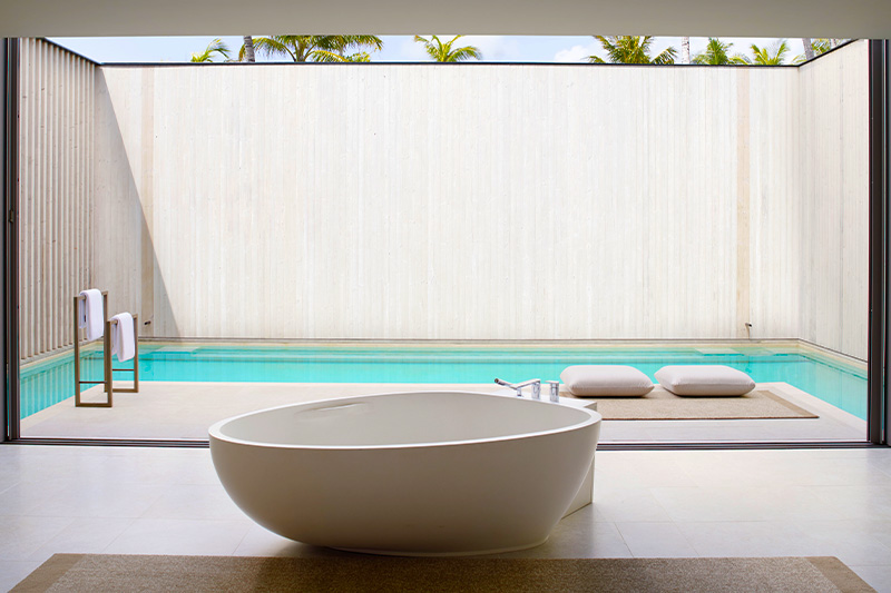 bathtub with an open view and pool outside