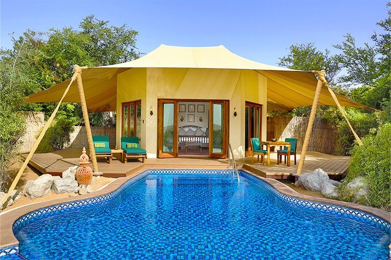 A canopy room with a sparkling pool at Al Maha Desert Resort and Spa